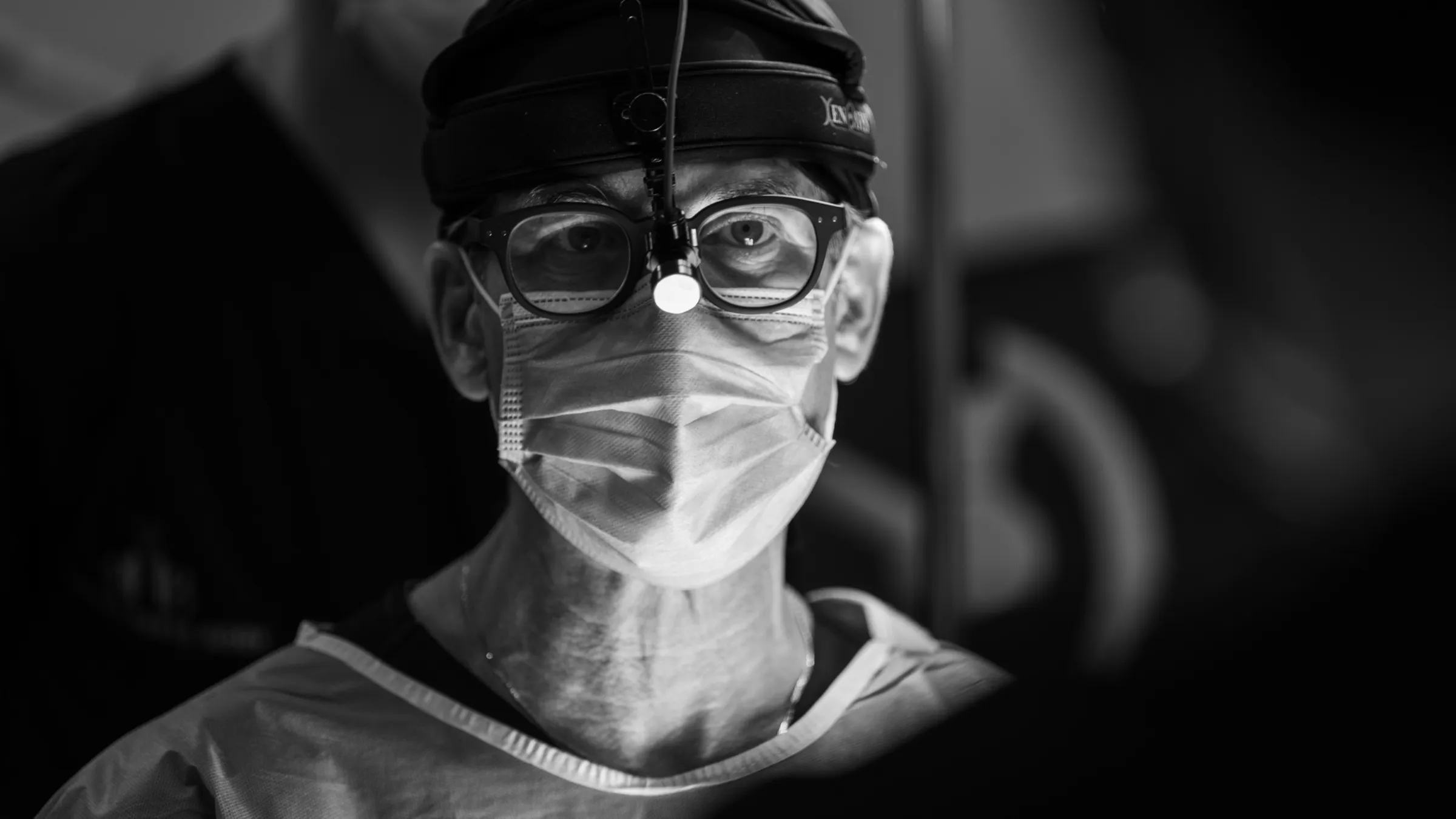 Portrait en noir et blanc d’un chirurgien avec lampe frontale